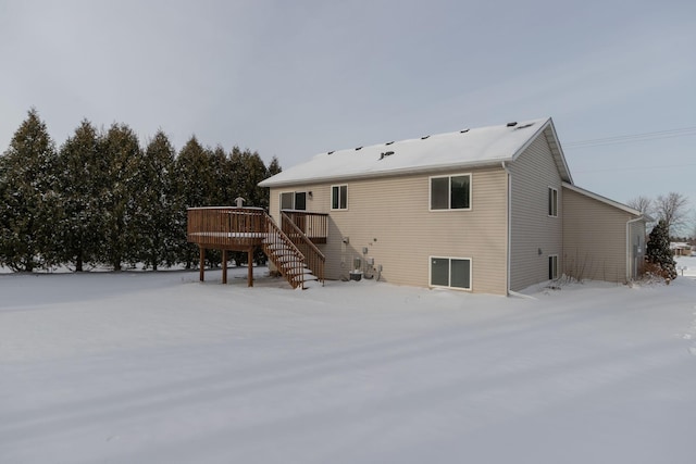 snow covered back of property featuring a deck