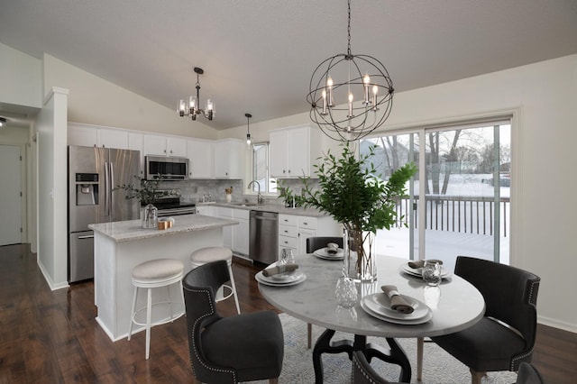 dining space with dark wood-type flooring, a chandelier, vaulted ceiling, and sink