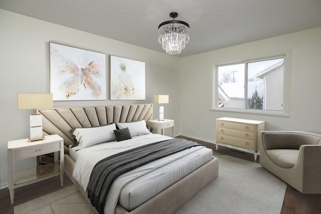 bedroom featuring hardwood / wood-style flooring, a textured ceiling, and an inviting chandelier