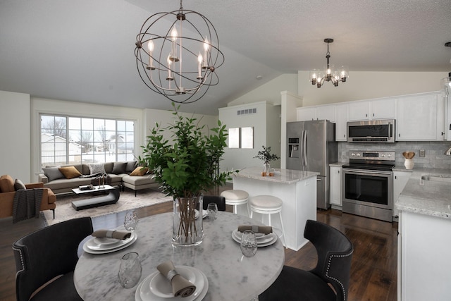 dining space with dark hardwood / wood-style flooring, a chandelier, vaulted ceiling, and sink