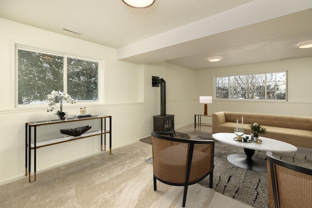 living room featuring light colored carpet and a wood stove