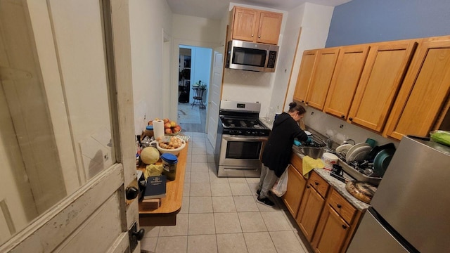 kitchen featuring sink, light tile patterned flooring, and appliances with stainless steel finishes