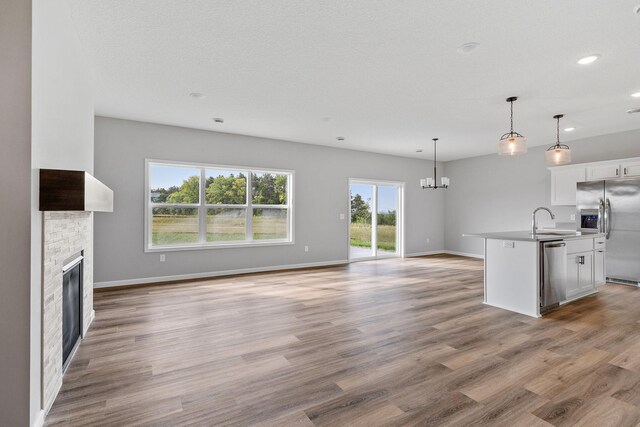 kitchen featuring sink, white cabinetry, hanging light fixtures, a center island with sink, and stainless steel appliances