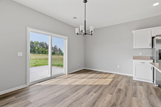 unfurnished dining area featuring a notable chandelier and light hardwood / wood-style floors