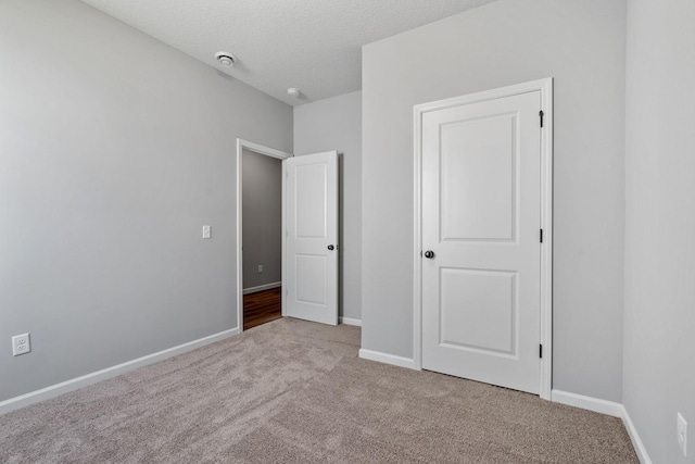 unfurnished bedroom featuring light carpet and a textured ceiling