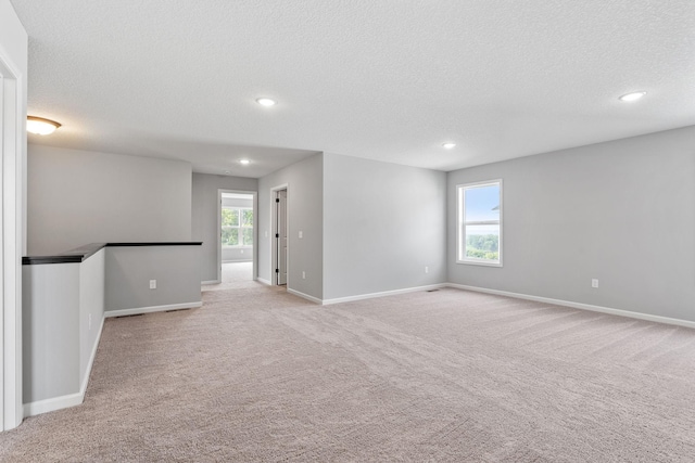 carpeted empty room with a healthy amount of sunlight and a textured ceiling