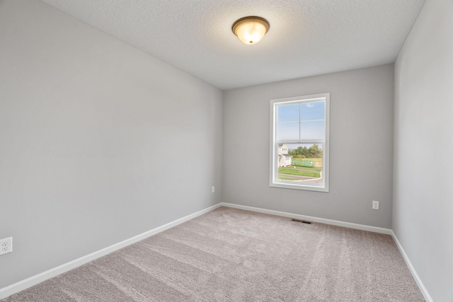 carpeted empty room featuring a textured ceiling