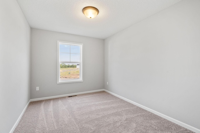 carpeted empty room featuring a textured ceiling