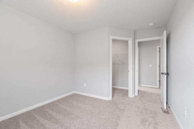 unfurnished bedroom with light carpet, a textured ceiling, and a closet