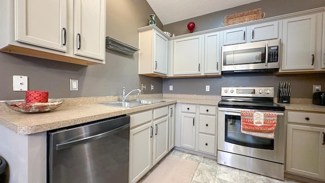 kitchen featuring white cabinetry, sink, stainless steel appliances, and a textured ceiling