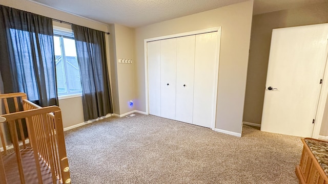 unfurnished bedroom with carpet floors, a textured ceiling, and a closet