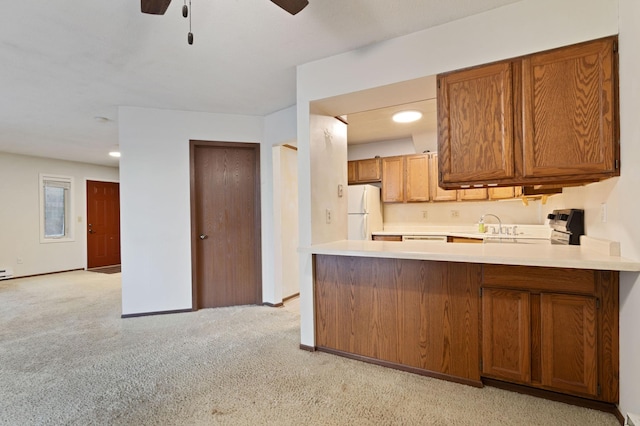 kitchen with kitchen peninsula, white refrigerator, light colored carpet, and ceiling fan