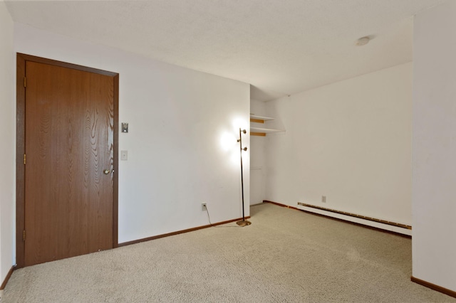 empty room with light colored carpet and a baseboard heating unit