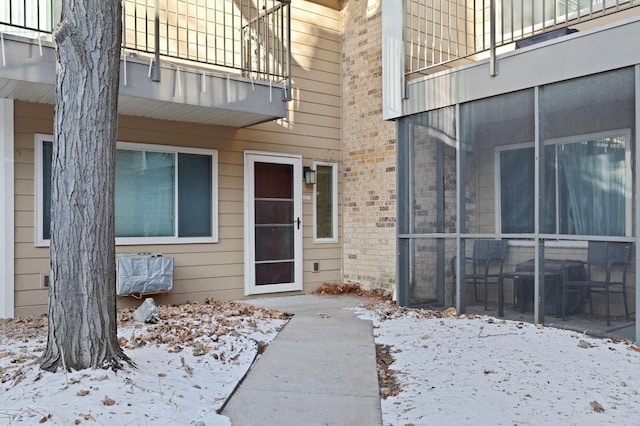 snow covered property entrance with a balcony