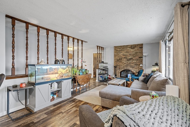 living room featuring wood-type flooring, a textured ceiling, and a brick fireplace