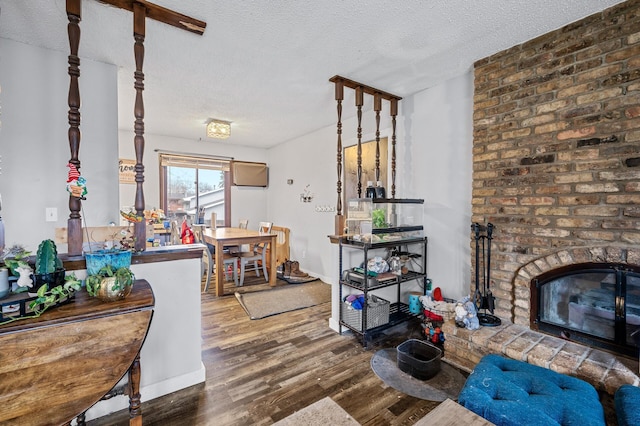 living room featuring a brick fireplace, a textured ceiling, and hardwood / wood-style flooring