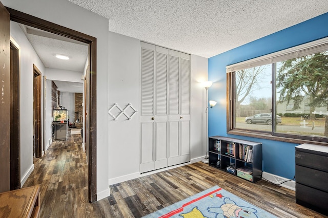 interior space featuring a textured ceiling, a closet, and dark hardwood / wood-style floors