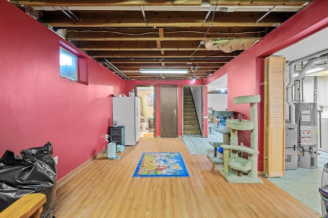 basement with hardwood / wood-style floors, white fridge, and water heater