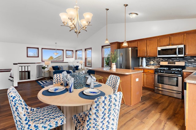 kitchen featuring stainless steel appliances, tasteful backsplash, lofted ceiling, decorative light fixtures, and a kitchen island