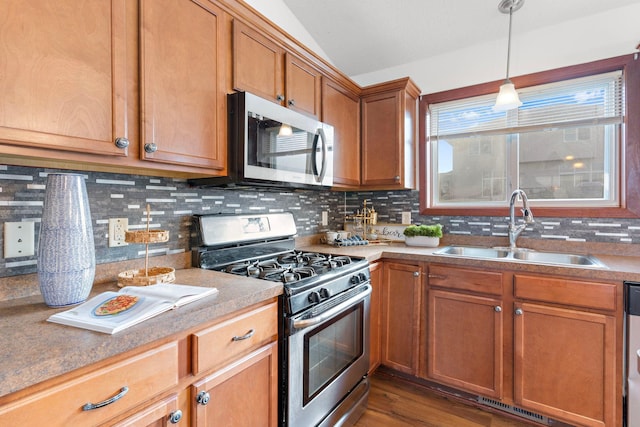 kitchen featuring appliances with stainless steel finishes, backsplash, dark wood-type flooring, sink, and hanging light fixtures