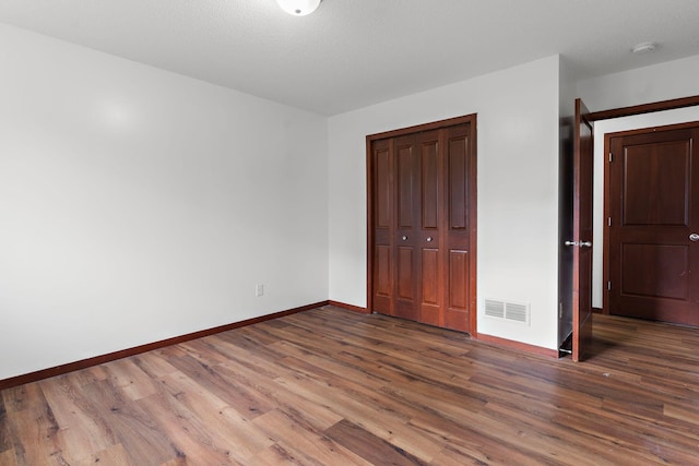 unfurnished bedroom featuring dark hardwood / wood-style flooring and a closet