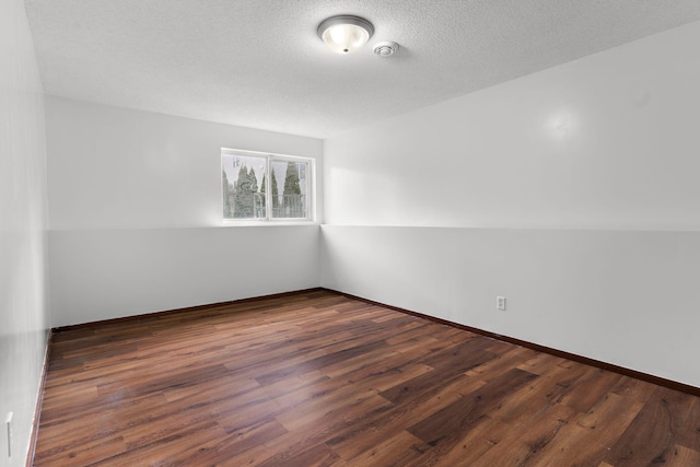 unfurnished room with a textured ceiling and dark hardwood / wood-style flooring