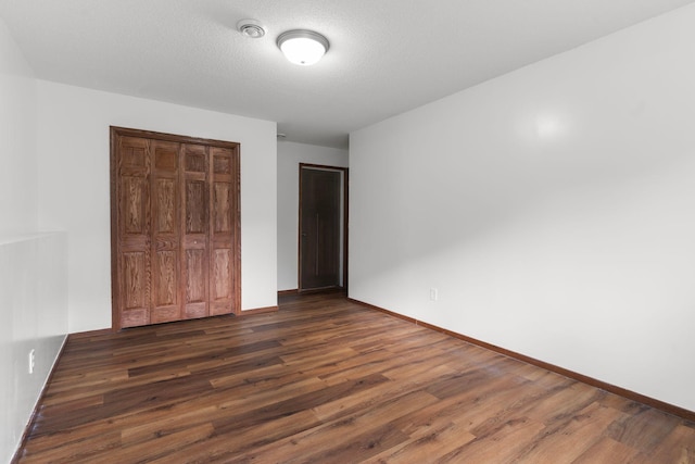 unfurnished bedroom with dark hardwood / wood-style flooring, a textured ceiling, and a closet