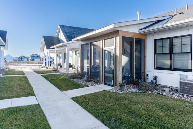 exterior space with a sunroom, a yard, and cooling unit