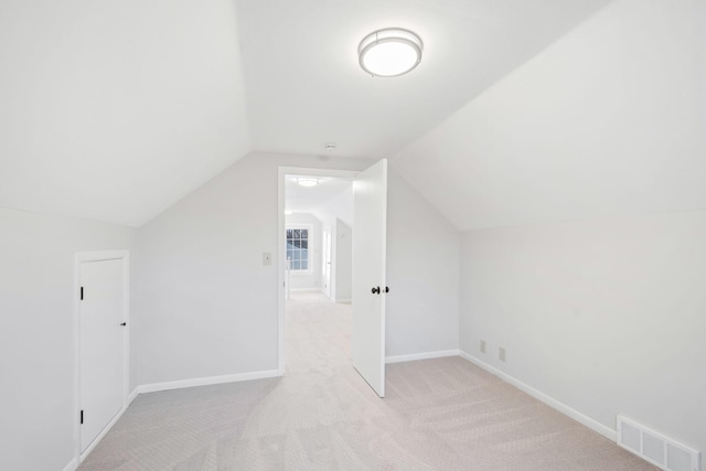 bonus room with light carpet and vaulted ceiling