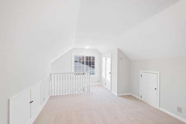 additional living space featuring light carpet and vaulted ceiling