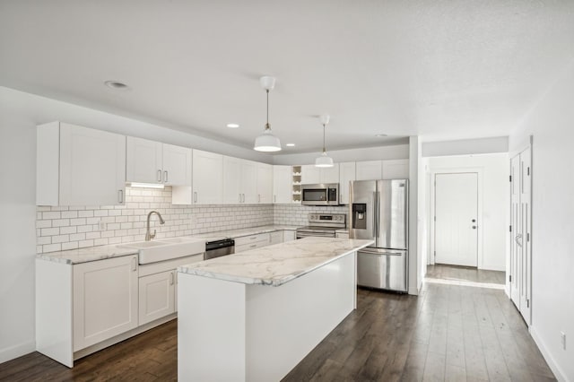 kitchen with sink, a center island, decorative light fixtures, white cabinets, and appliances with stainless steel finishes