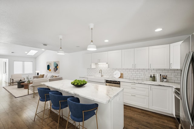 kitchen with stainless steel appliances, white cabinetry, and decorative light fixtures