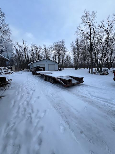 yard layered in snow with a garage and an outdoor structure