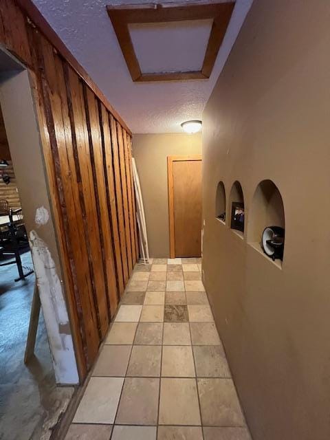 hallway featuring light tile patterned flooring and a textured ceiling