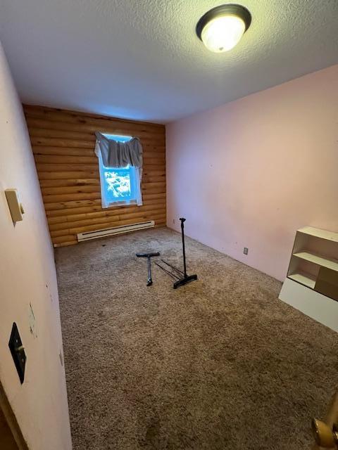 exercise room with carpet, a textured ceiling, and a baseboard heating unit