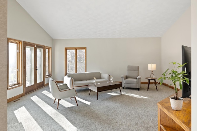 carpeted living room featuring high vaulted ceiling and french doors