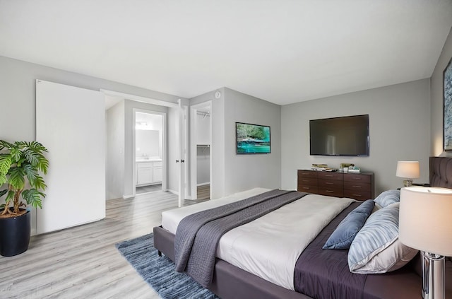 bedroom featuring light wood-type flooring and connected bathroom