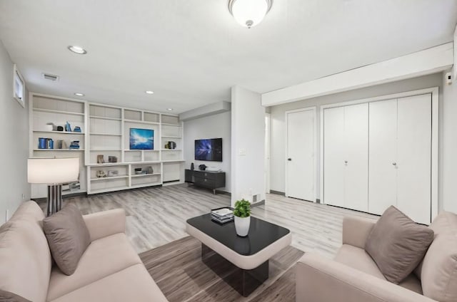 living room featuring light wood-type flooring and built in features