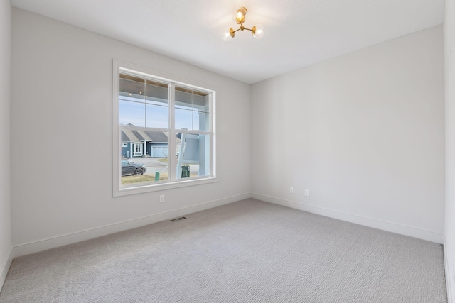 spare room with carpet flooring and a notable chandelier