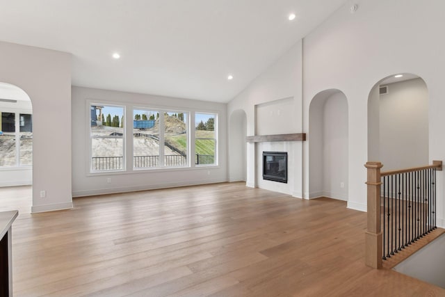 unfurnished living room featuring high vaulted ceiling and light wood-type flooring