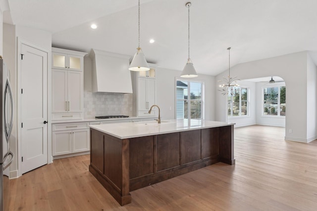 kitchen featuring vaulted ceiling, light hardwood / wood-style flooring, white cabinets, and custom range hood