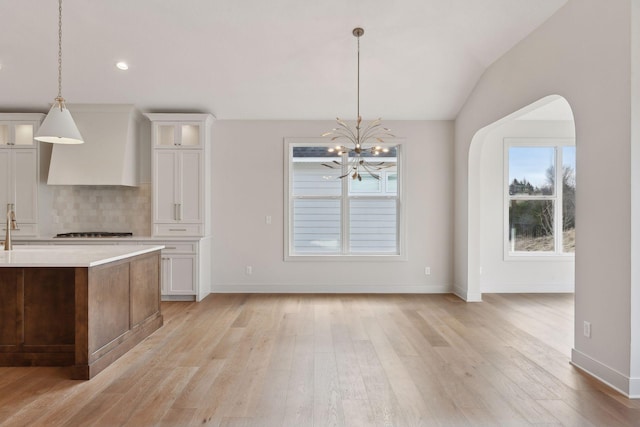 kitchen with white cabinetry, hanging light fixtures, light hardwood / wood-style floors, and stainless steel gas cooktop