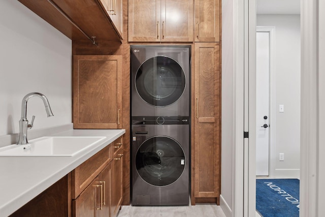 laundry room with sink, cabinets, and stacked washer / drying machine