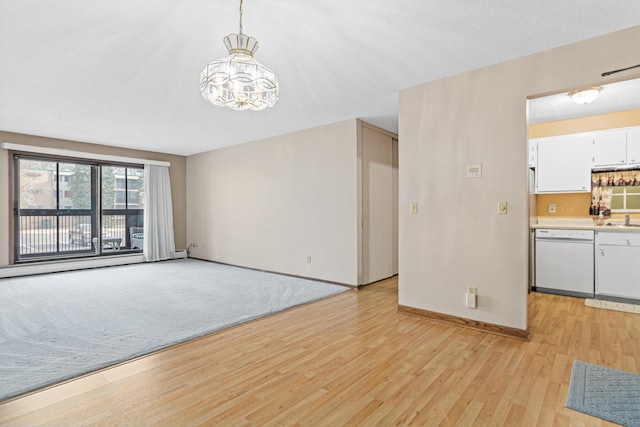 unfurnished living room featuring a textured ceiling, sink, a baseboard radiator, light hardwood / wood-style flooring, and a notable chandelier