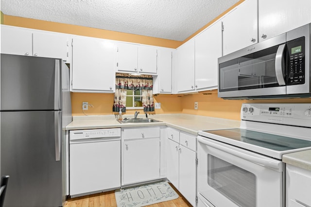 kitchen with a textured ceiling, stainless steel appliances, sink, light hardwood / wood-style flooring, and white cabinetry