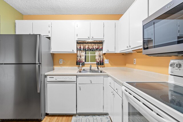 kitchen featuring white cabinets, a textured ceiling, stainless steel appliances, and sink