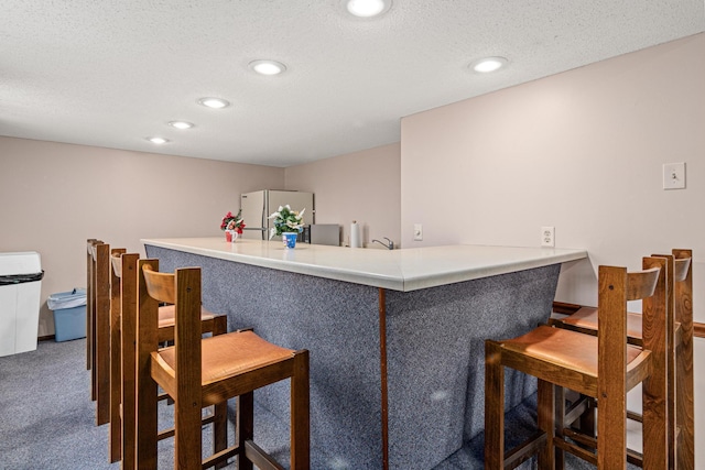 bar with carpet floors, a textured ceiling, and white refrigerator