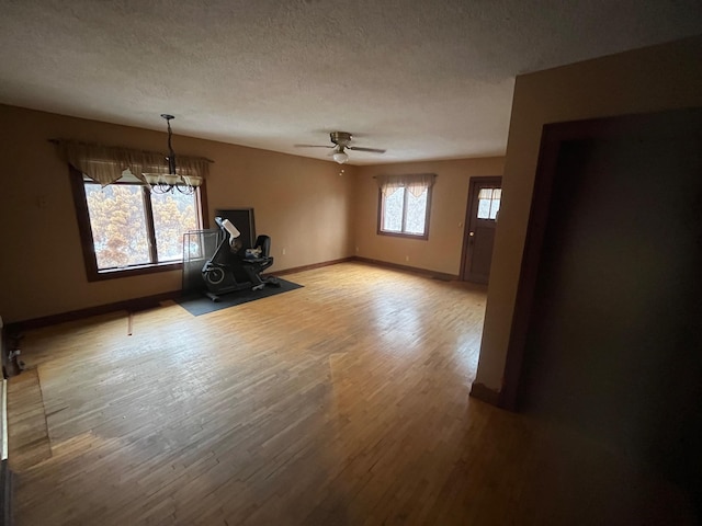 interior space featuring hardwood / wood-style flooring, ceiling fan with notable chandelier, and a textured ceiling