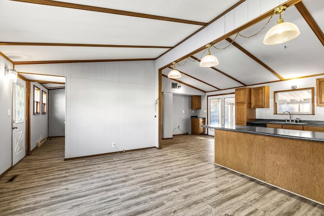 kitchen featuring wood walls, lofted ceiling with beams, sink, hanging light fixtures, and light hardwood / wood-style floors