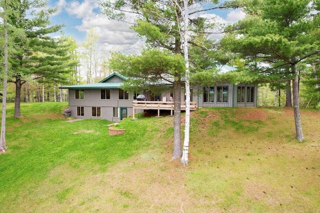 rear view of house featuring a sunroom, a deck, and a lawn